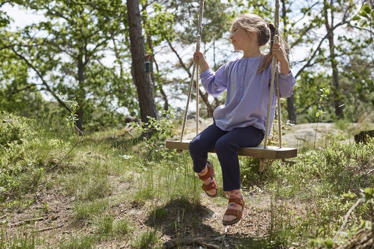 A-happy-kid-swings-on-a-sunny-day-wearing-clothes-dried-outside.jpg