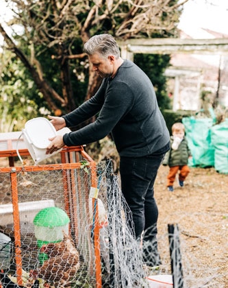 Massimo Mele feeding chickens in chicken coop